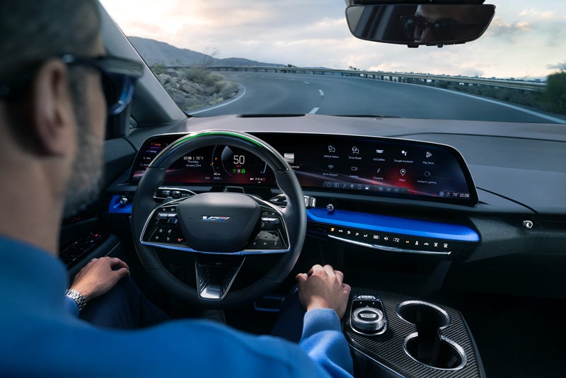 Front View of the 2026 OPTIQ-V Driving Through the Dusk Utilizing its Headlights | Jim Winter Cadillac in Jackson MI