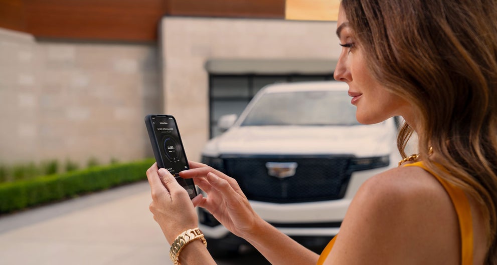 lady checking her mobile with a Cadillac vehicle background | Jim Winter Cadillac in Jackson MI